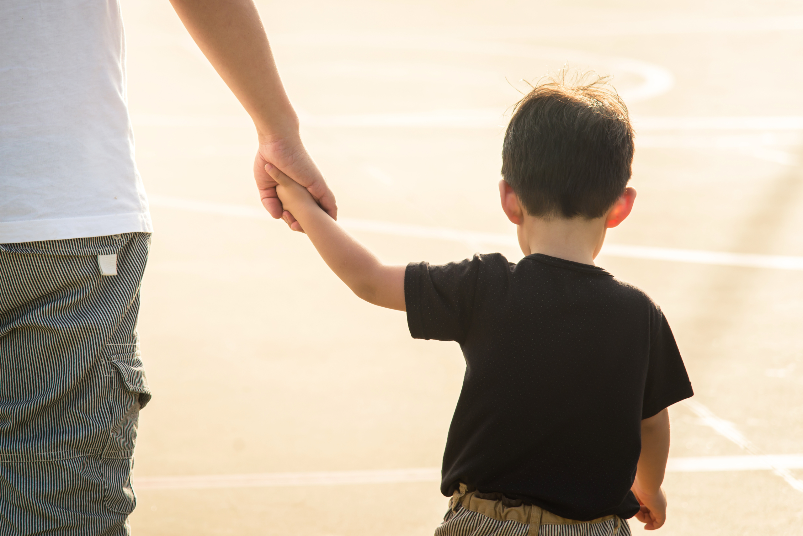father's hand lead his child son under sun light