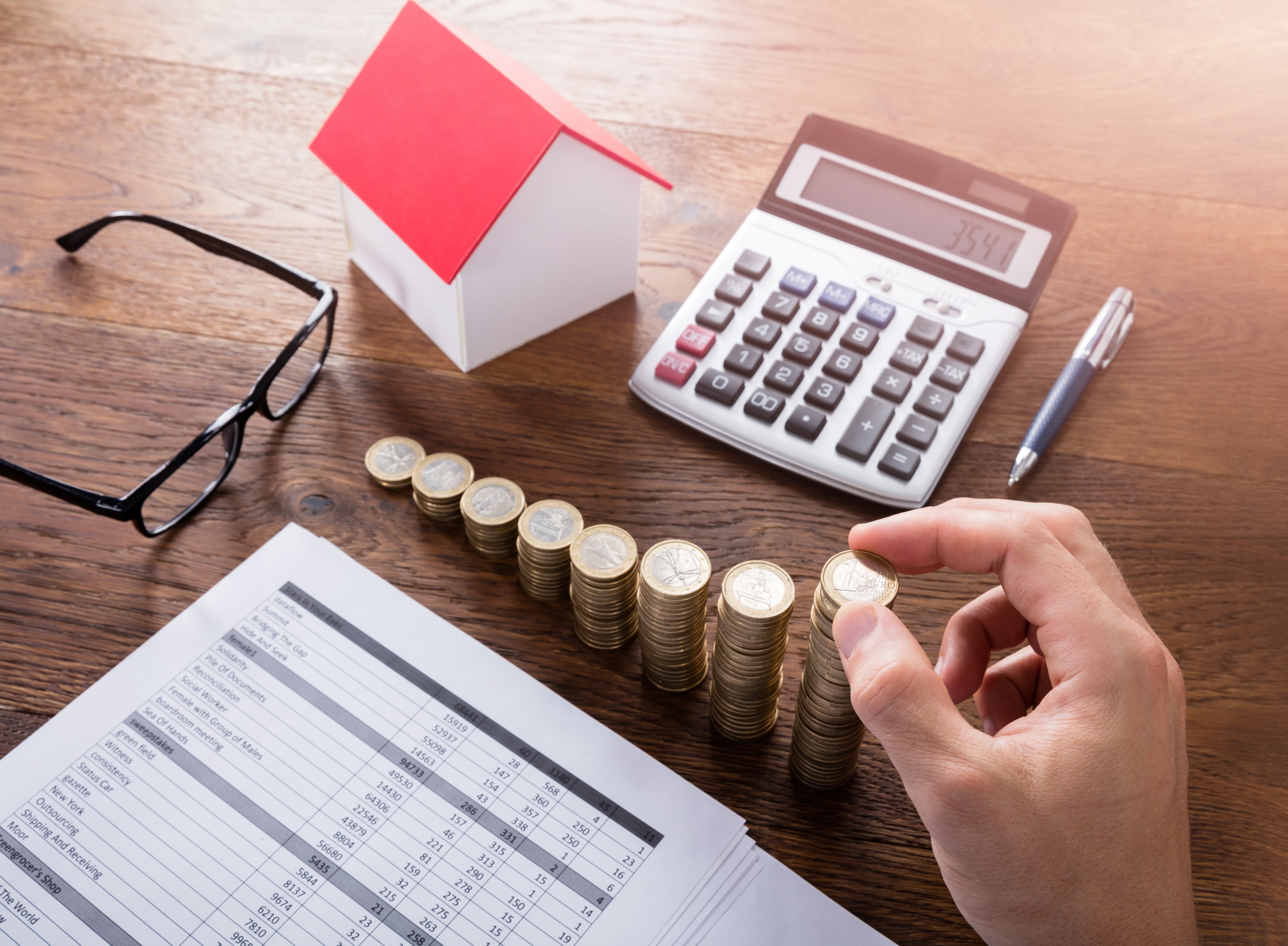 Person Stacking Coins On Wooden Desk